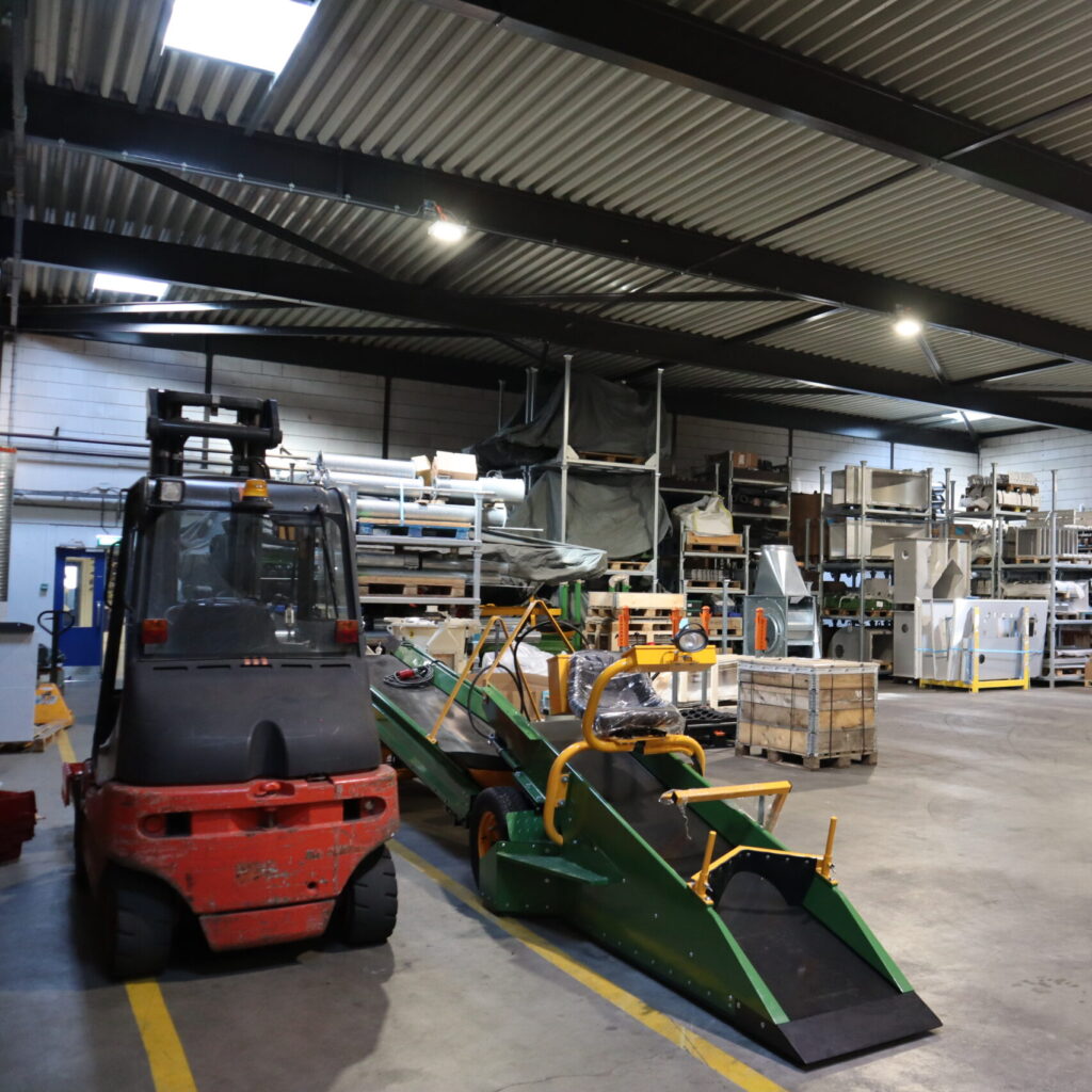 Opslaghal met heftruck, transportsystemen en machineonderdelen